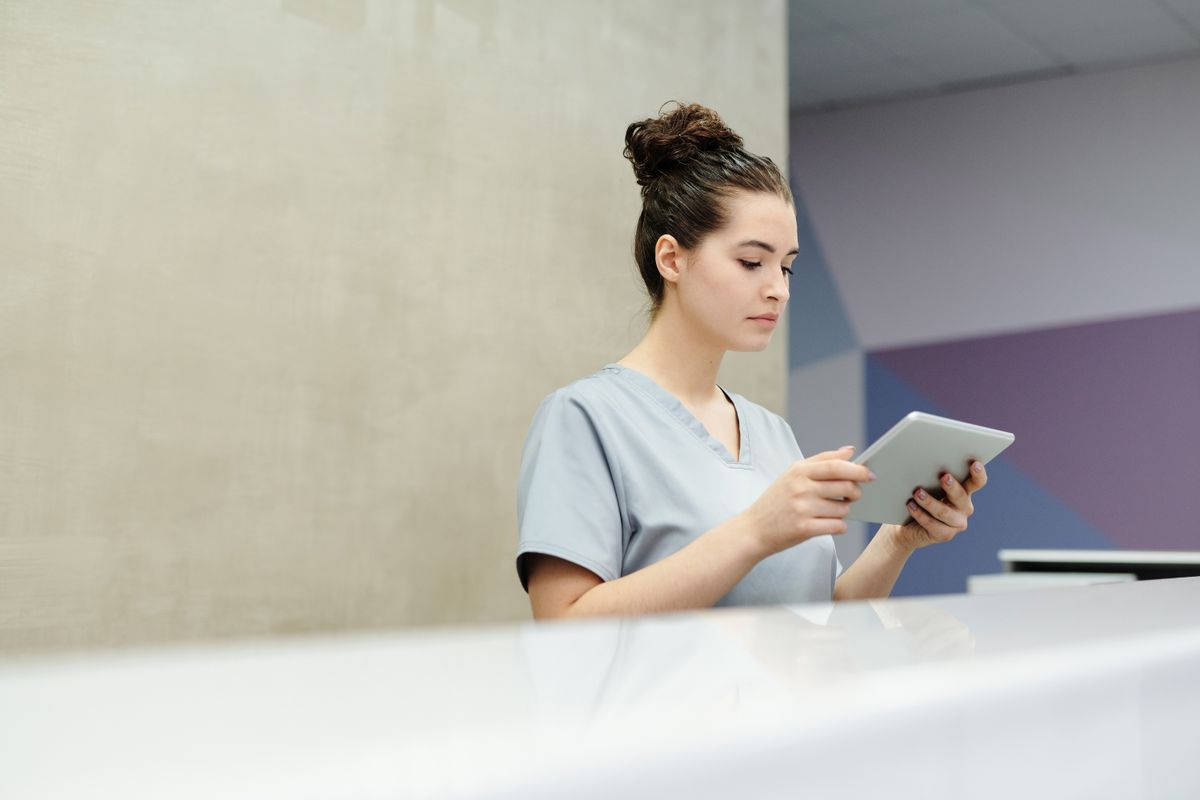 Medical office receptionist using a tablet at the front desk